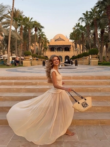 Close-up of elegant beige lace bodice and layered chiffon maxi dress in a resort setting