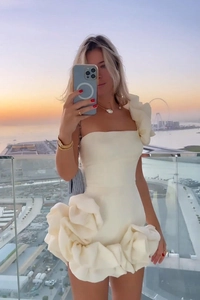 Détail d'une robe moulante blanche avec de grandes fleurs 3D sur la jupe au crépuscule