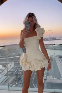 Détail d'une mini robe blanche bustier avec volants floraux superposés et texture plissée