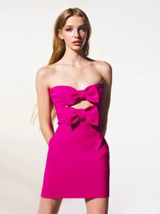 Detail van strapless fuchsia mini-jurk met oversized gelaagde strik en een uitsparing