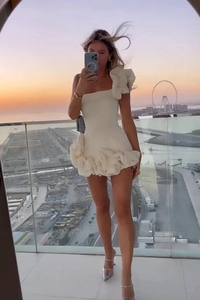 Détail de robe blanche élégante à épaules dénudées avec volants floraux 3D et taille ajustée