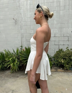 Detail of white off-shoulder mini dress featuring ruffled hem and cinched waistline