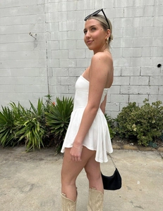 Detailed view of white off-the-shoulder corset dress with pleated skirt in outdoor light