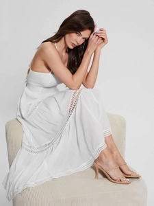 Detailed view of white maxi dress with lace cutouts and layered cake-style skirt texture