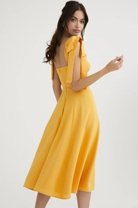 Detailed view of yellow French style dress showing large bow straps and waist tailoring