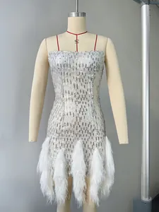 Détail d'une robe à paillettes argentées avec plumes blanches luxueuses sur l'ourlet bas