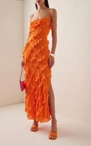Détail d'une robe orange à volants avec de fines bretelles et une fente latérale