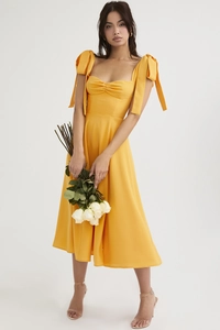 Detail of a bright yellow midi dress featuring oversized shoulder bows and ruched bodice