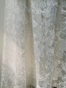 Detailed close-up of intricate white leaf embroidery on delicate mesh lace fabric