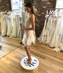 Détail de la robe à paillettes blanches avec bordure en plumes blanches élégantes sur l'ourlet