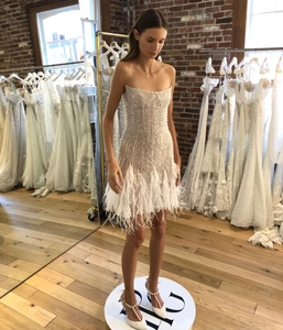 Détails d'une robe de cocktail à paillettes blanches avec perles et bordure en plumes