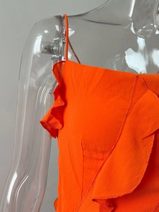 Détail d'une robe plissée orange vif avec des volants délicats et de fines bretelles