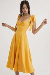 Detail of a bright yellow dress with elegant bow straps and a gathered sweetheart neckline