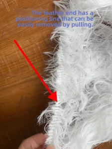 Detail showing the removable positioning line on the white feather trim of the dress
