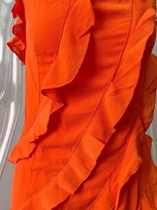 Détails rapprochés des volants orange vif sur une robe d'été fendue à texture verticale fine
