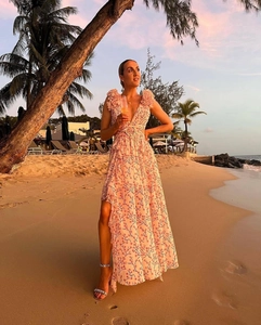 Détail d'une robe longue rose à fleurs avec décolleté en V, volants et fente latérale