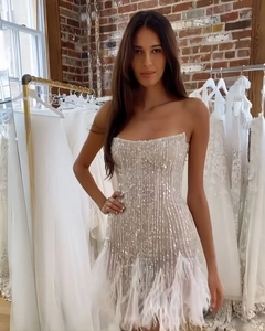 Détail de la robe à paillettes argentées avec une élégante bordure en plumes blanches
