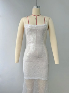 Close-up of white sequin cocktail dress with thin straps and sheer mesh hemline detail