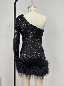Détail de la robe à paillettes noire avec épaule dénudée et bordure en plumes chic
