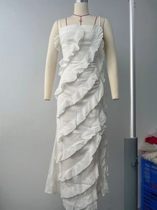 Détail des volants verticaux sur une robe longue blanche élégante avec fente latérale