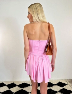 Back view of a pink bodycon mini dress with structured boning and pleated skirt detail