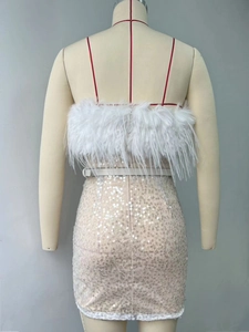 Détail de plumes blanches et de paillettes dorées scintillantes sur une mini robe chic