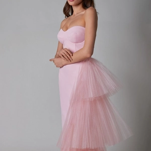 Detail of pink strapless party dress featuring voluminous layered mesh ruffles and slit