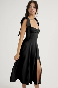 Detail of elegant black sundress featuring shoulder bow ties and a high side slit