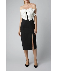 Detail of elegant tube midi dress featuring a large white bow and black side slit design