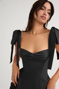 Detail of black sweetheart neckline dress featuring elegant shoulder bow ties and pleats