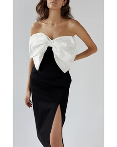 Detailed view of elegant strapless dress featuring a large white bow and high side slit