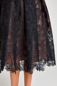 Close-up of black lace hem with floral embroidery and nude lining on evening dress