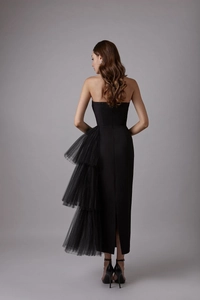 Rear view of slim fit black strapless dress featuring layered tulle and back slit detail