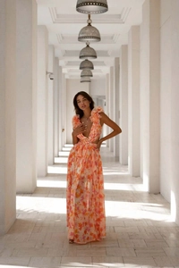 Détail d'une robe maxi florale avec col en V profond, manches à volants et découpe à la taille