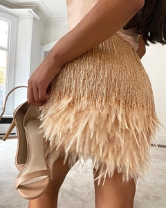 Detailed view of champagne gold mini skirt featuring beaded fringe and feather trim