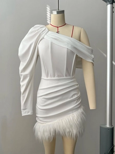 Detail of white asymmetric dress showing feather trim and corset-style pleated bodice