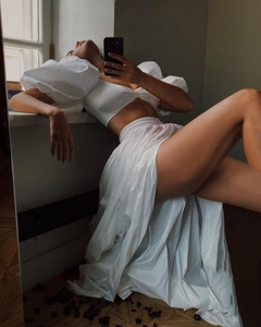 Detailed mirror selfie of white two-piece set featuring puff sleeve top and high slit skirt