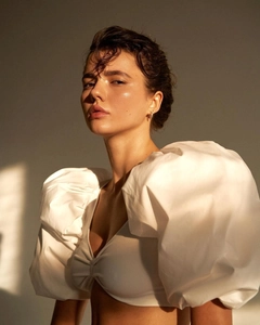 Close-up of a white deep V-neck top with dramatic puff sleeves and pleated center detail