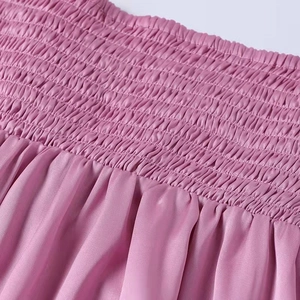 Detail of pink satin dress featuring elegant smocked waist and soft pleated texture