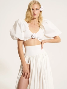 Detail of white two-piece set featuring puff sleeves with 3D floral accents and high slit skirt