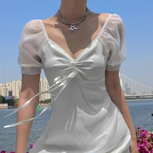 Detail of white satin dress featuring puffy sleeves and long tassel ribbons on the chest