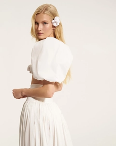 Detail of white puff sleeve crop top and high waist pleated skirt set with floral headpiece