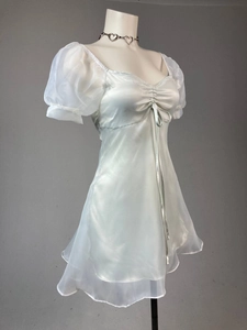 Detail of silver satin dress featuring organza puff sleeves and ruffled hem with necklace