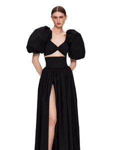 Detail of high-slit pleated skirt and puff sleeve crop top set in black woven fabric