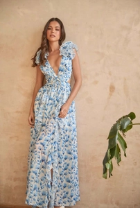Détail d'une robe longue fleurie bleue avec décolleté en V et volants sur les épaules