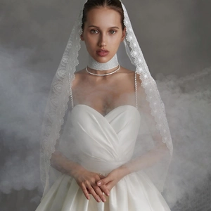 Détail d'une robe de mariée en satin blanc avec choker en strass et voile en dentelle