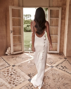 Detail of white satin backless dress with thin straps and 3D floral accents