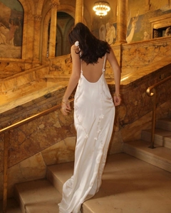 Close-up of 3D floral appliqués on backless white satin dress with delicate straps