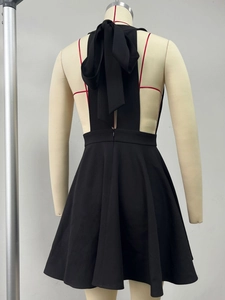 Detail of sexy backless black dress featuring a large bow tie and halter neckline design