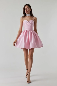 Détail de robe cocktail en satin rose avec décolleté plissé et bretelles en strass